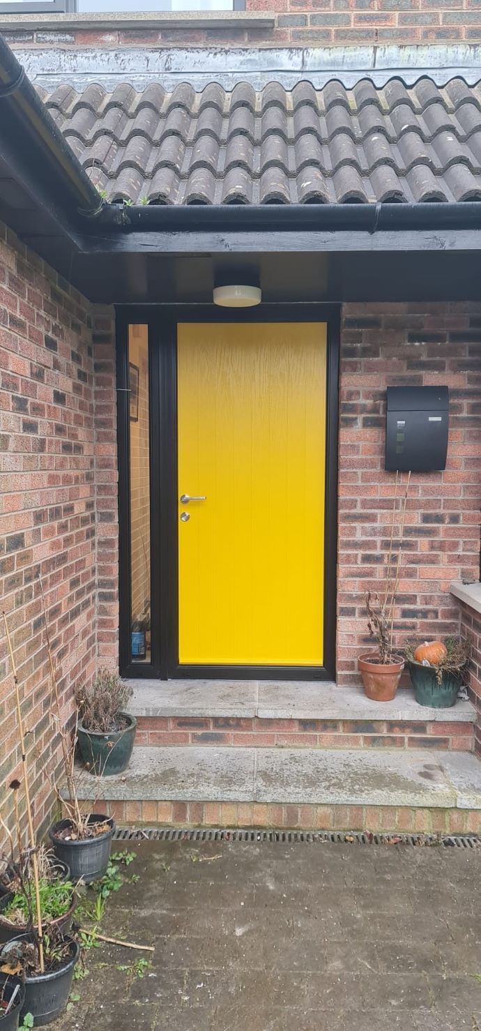 external view of installation of yellow composite door with black frame